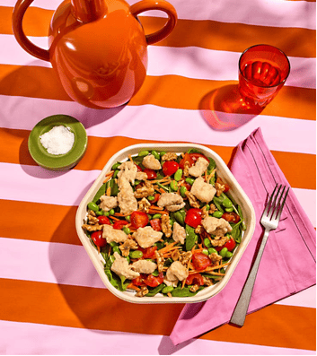 Salade servie sur une nappe rayée orange et rose